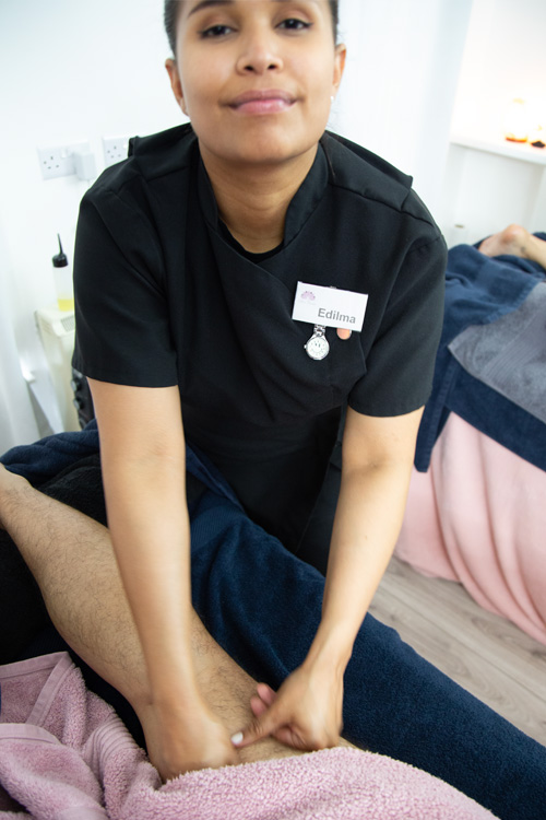 Massage therapist Edilma Torrez confidently performs a leg massage, exemplifying the skilled care at Edilma Therapy.