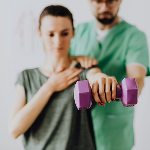 A physiotherapist is securing a patient with a safety strap before starting a specialised treatment on a therapy table